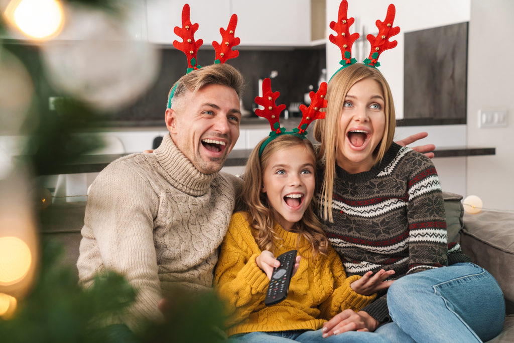 Cheerful family sitting together on a couch at the living room at Christmas